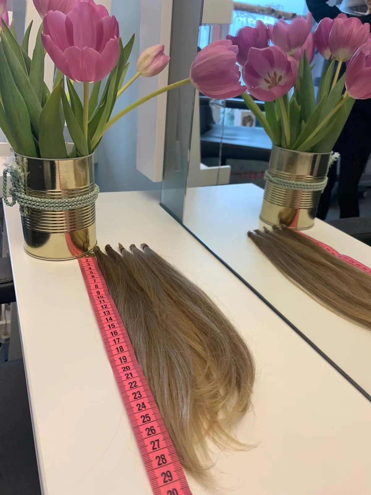 Haarverlängerungs-Tressen auf dem Bedienplatz mit pinken Tulpen